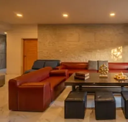 The Long House living room: red leather sofas around a low table under warm lights
